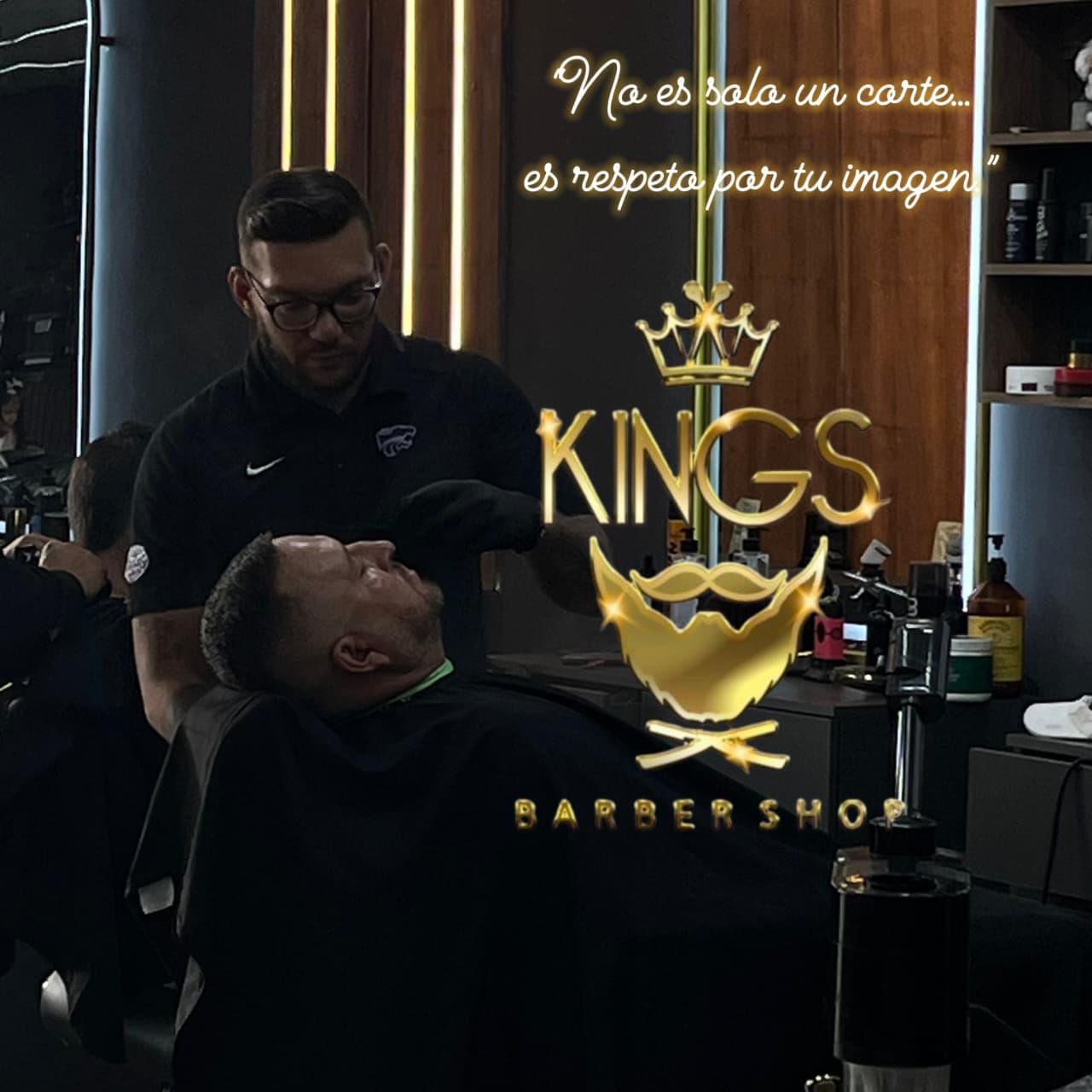 Barbero arreglando la barba de un cliente frente al letrero de Kings